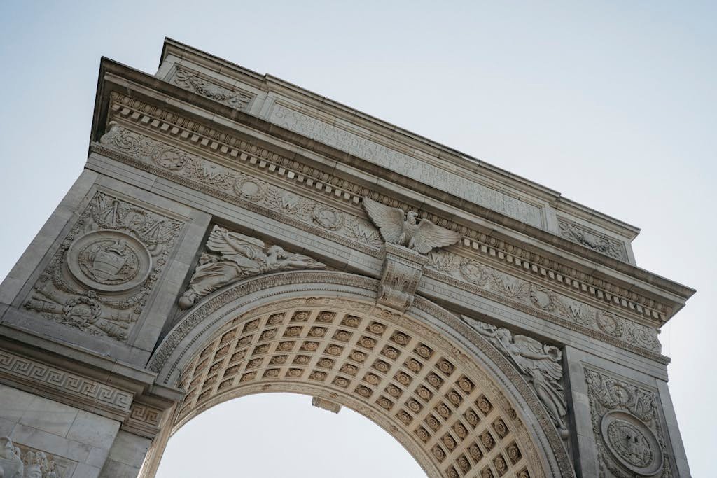 From below of aged architectural monument with ornamental columns and arched passage located in Washington Square Park