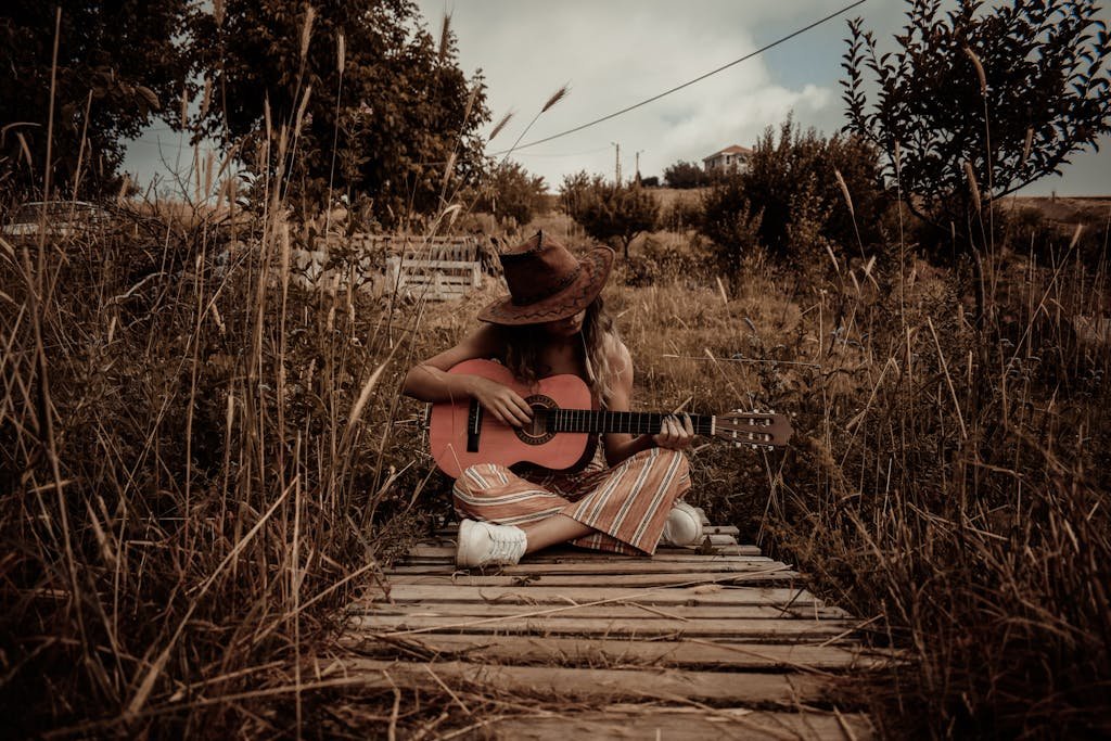 Woman Holding Guitar Sitting On Dock