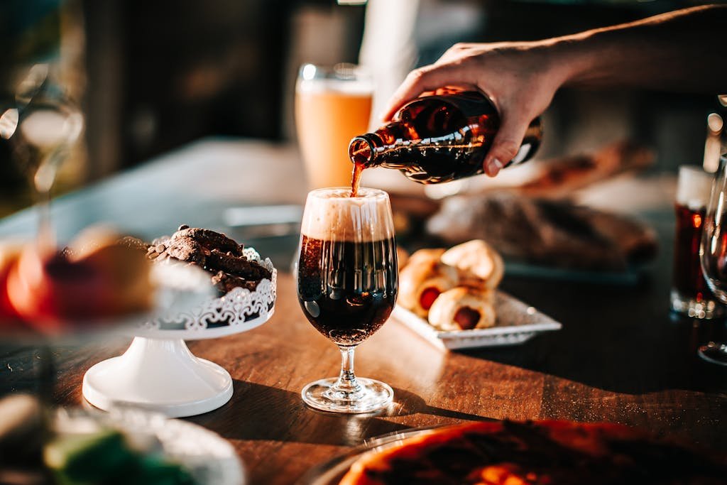 Person Pouring Drink On Wine Glass