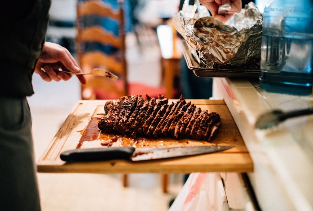 Person Holding Knife Slicing Meat