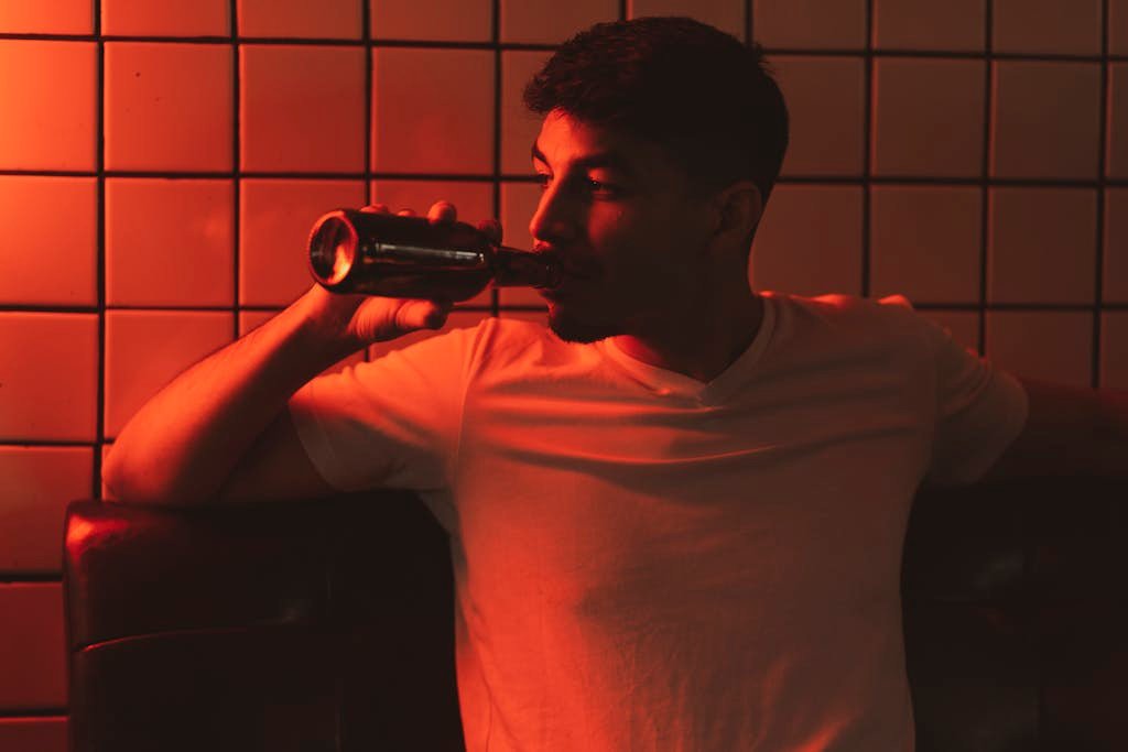 Man in White V Neck T Shirt Drinking from Bottle