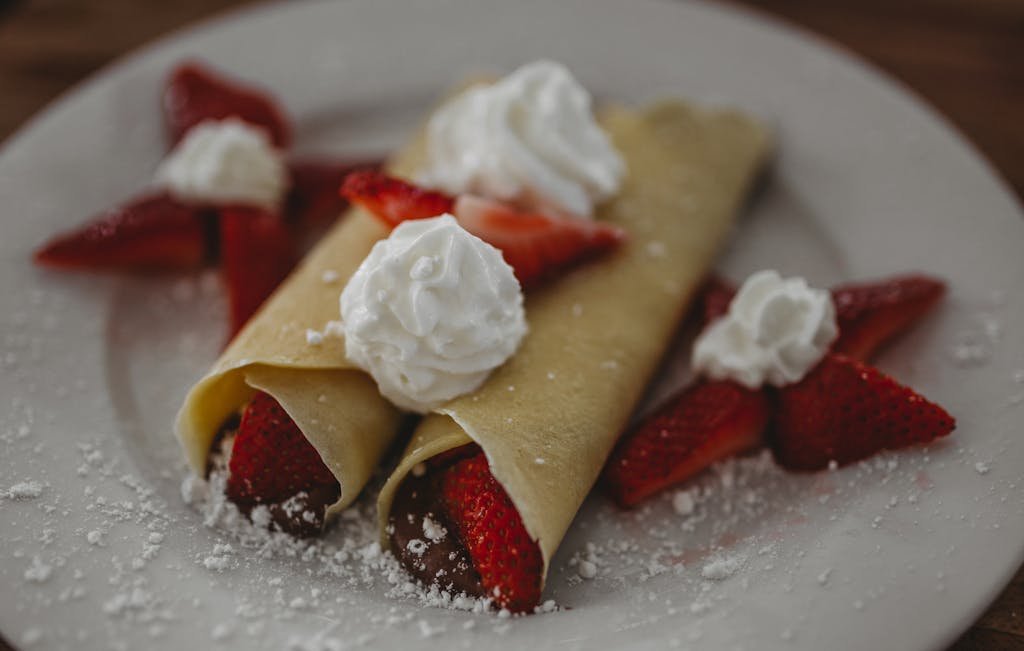 Freshly made strawberry crepes topped with whipped cream, perfect for a delightful breakfast or dessert.